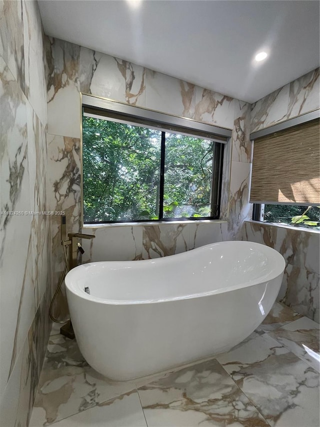 5811 SW 33rd Ter, Hollywood, FL 33312 - bathroom featuring marble tiled floors, a freestanding tub, stone wall, and tile walls