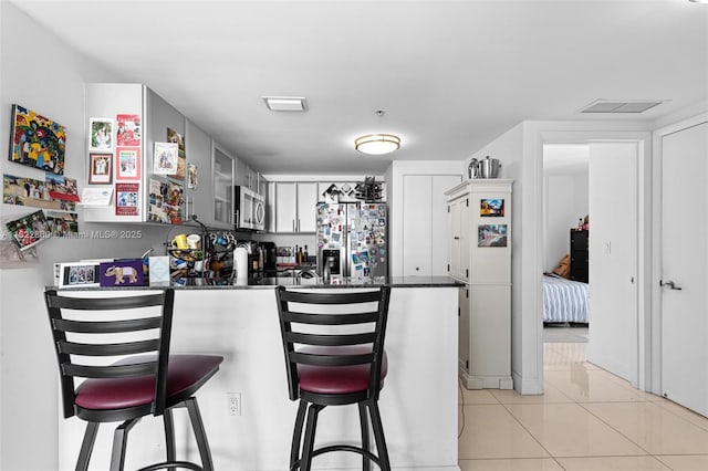 1861 NW S River Dr Unit Ph-01, Miami, FL 33125 - kitchen featuring appliances with stainless steel finishes, a peninsula, dark countertops, a kitchen bar, and light tile patterned floors