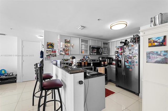 1861 NW S River Dr Unit Ph-01, Miami, FL 33125 - kitchen with stainless steel appliances, a peninsula, dark countertops, a breakfast bar area, and glass insert cabinets