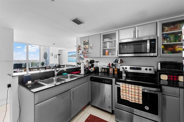 1861 NW S River Dr Unit Ph-01, Miami, FL 33125 - kitchen featuring appliances with stainless steel finishes, gray cabinetry, a peninsula, light tile patterned floors, and dark countertops