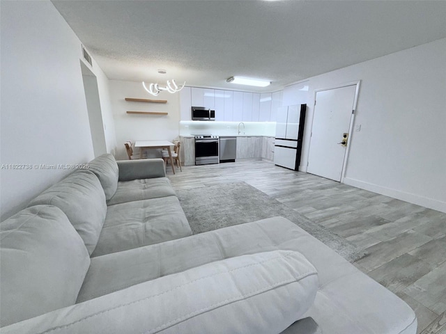 9352 S Belfort Cir Unit 109, Tamarac, FL 33321 - living room featuring a chandelier, light wood-style floors, and a textured ceiling
