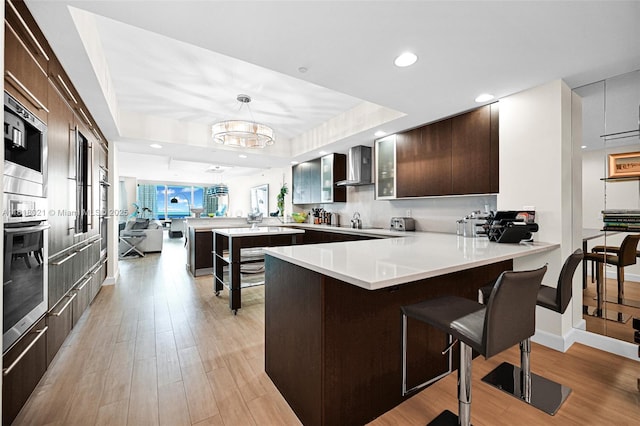 2711 S Ocean Dr Unit 3003, Hollywood, FL 33019 - kitchen with a peninsula, modern cabinets, wall chimney range hood, light wood-type flooring, and dark brown cabinets