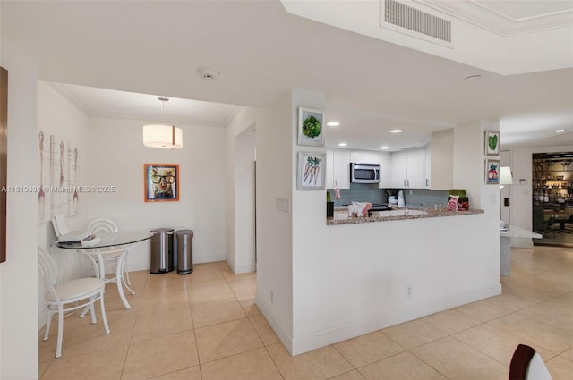 140 SE 5th Ave Unit 438, Boca Raton, FL 33432 - kitchen with stainless steel microwave, light tile patterned flooring, white cabinetry, tasteful backsplash, and recessed lighting