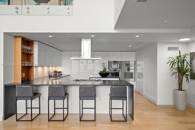 4701 N Meridian Ave Unit 217, Miami Beach, FL 33140 - kitchen with modern cabinets, island range hood, a peninsula, dark countertops, and recessed lighting