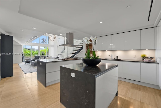 4701 N Meridian Ave Unit 217, Miami Beach, FL 33140 - kitchen with modern cabinets, island exhaust hood, a center island, dark countertops, and white cabinetry