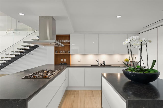 4701 N Meridian Ave Unit 217, Miami Beach, FL 33140 - kitchen with modern cabinets, island exhaust hood, stainless steel gas cooktop, dark countertops, and white cabinets