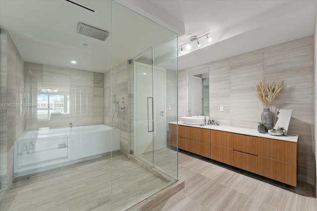 4701 N Meridian Ave Unit 217, Miami Beach, FL 33140 - bathroom with a garden tub, vanity, a shower stall, tile walls, and rail lighting