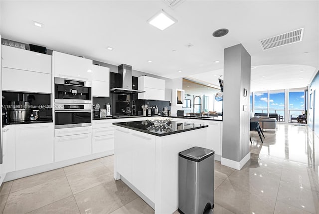 17121 Collins Ave Unit 2304, Sunny Isles Beach, FL 33160 - kitchen featuring stainless steel oven, dark countertops, wall chimney exhaust hood, modern cabinets, and a center island