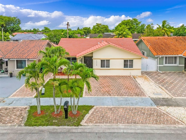 14548 SW 98th Ter, Miami, FL 33186 - view of front facade with stucco siding, a tiled roof, a gate, and driveway
