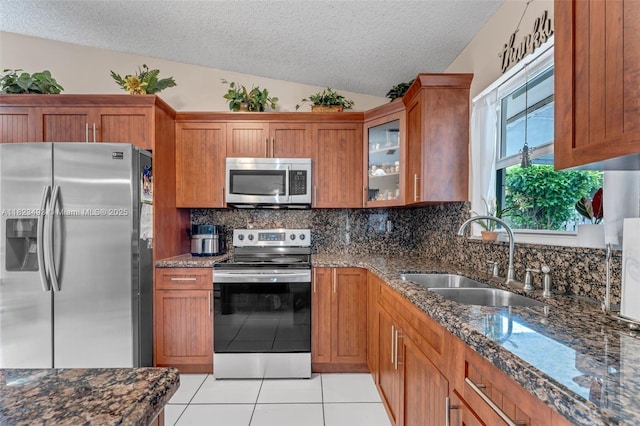 14548 SW 98th Ter, Miami, FL 33186 - kitchen featuring appliances with stainless steel finishes, a textured ceiling, brown cabinetry, light tile patterned flooring, and tasteful backsplash