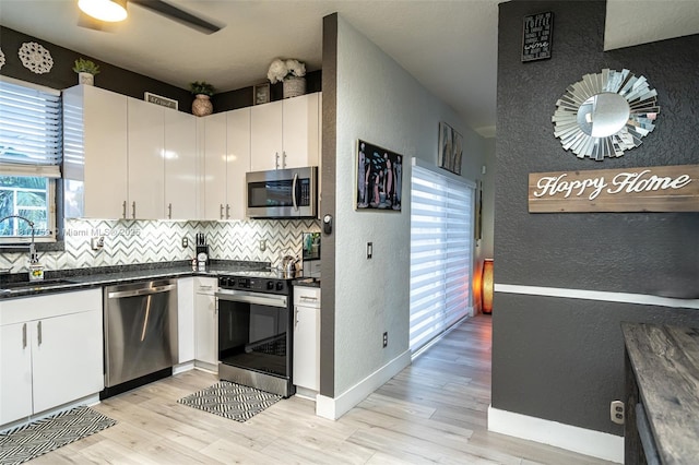 13290 SW 54th Ct, Miramar, FL 33027 - kitchen with stainless steel appliances, a textured wall, dark countertops, decorative backsplash, and light wood-style flooring