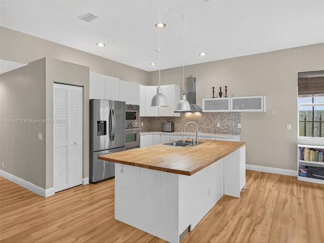 782 Lake Blvd, Weston, FL 33326 - kitchen with stainless steel appliances, wooden counters, wall chimney range hood, white cabinets, and light wood-style flooring
