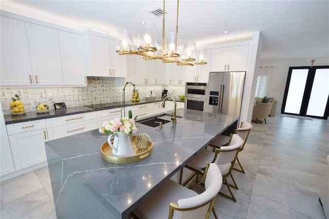 21420 SW 127th Pl, Miami, FL 33177 - kitchen featuring stainless steel appliances, a chandelier, an island with sink, decorative backsplash, and white cabinetry