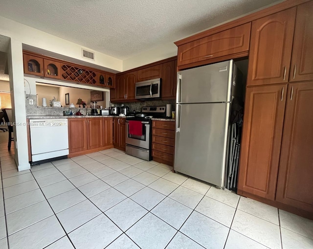 14901 SW 82nd Ter Unit 1-207, Miami, FL 33193 - kitchen with appliances with stainless steel finishes, light tile patterned floors, a textured ceiling, tasteful backsplash, and light countertops