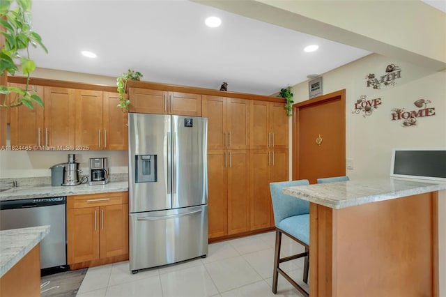 13705 SW 84th St Unit H, Miami, FL 33183 - kitchen with appliances with stainless steel finishes, brown cabinetry, a breakfast bar, light tile patterned flooring, and recessed lighting