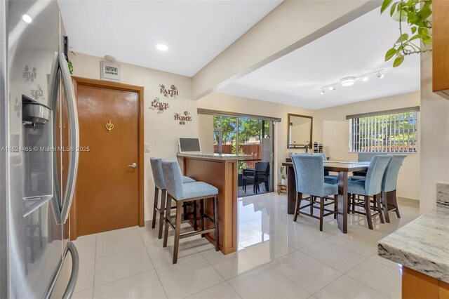 13705 SW 84th St Unit H, Miami, FL 33183 - kitchen featuring stainless steel refrigerator with ice dispenser, a kitchen bar, a peninsula, light tile patterned floors, and recessed lighting
