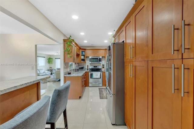 13705 SW 84th St Unit H, Miami, FL 33183 - kitchen featuring appliances with stainless steel finishes, light stone countertops, brown cabinets, glass insert cabinets, and recessed lighting