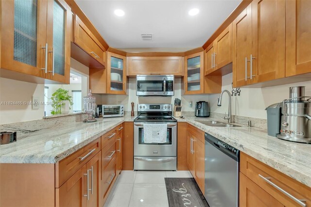 13705 SW 84th St Unit H, Miami, FL 33183 - kitchen featuring appliances with stainless steel finishes, light stone counters, light tile patterned floors, glass insert cabinets, and recessed lighting