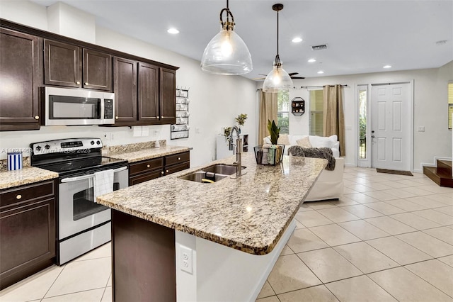 8144 Cascada Isles Dr, Cooper City, FL 33024 - kitchen with stainless steel appliances, light tile patterned floors, a center island with sink, dark brown cabinets, and recessed lighting