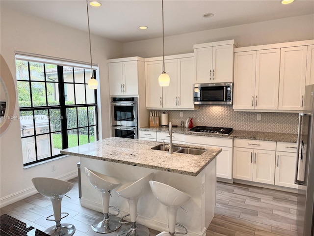 11455 Solstice Cir, Parkland, FL 33076 - kitchen with appliances with stainless steel finishes, light wood finished floors, tasteful backsplash, white cabinets, and light stone countertops