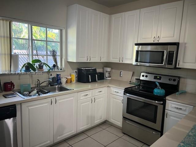 4812 Washington St Unit 8, Hollywood, FL 33021 - kitchen with stainless steel appliances, backsplash, and white cabinets