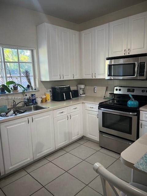 4812 Washington St Unit 8, Hollywood, FL 33021 - kitchen featuring appliances with stainless steel finishes, light countertops, white cabinetry, light tile patterned floors, and backsplash