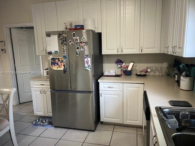 4812 Washington St Unit 8, Hollywood, FL 33021 - kitchen featuring freestanding refrigerator, white cabinets, light countertops, and backsplash