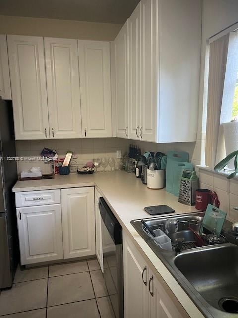 4812 Washington St Unit 8, Hollywood, FL 33021 - kitchen featuring dishwasher, white cabinetry, freestanding refrigerator, light tile patterned floors, and light countertops