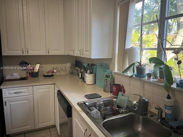 4812 Washington St Unit 8, Hollywood, FL 33021 - kitchen featuring dishwasher, white cabinetry, and tasteful backsplash