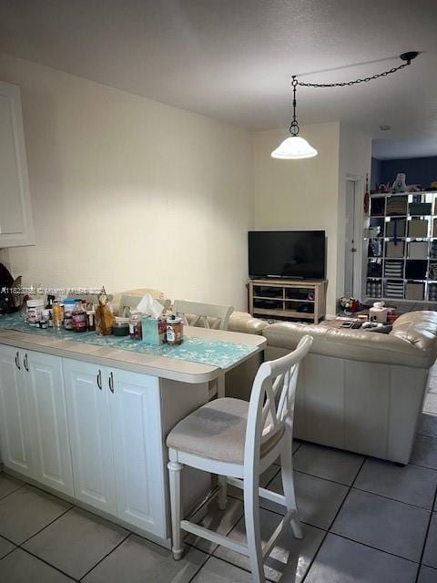 4812 Washington St Unit 8, Hollywood, FL 33021 - kitchen featuring white cabinetry, light tile patterned floors, light countertops, and hanging light fixtures