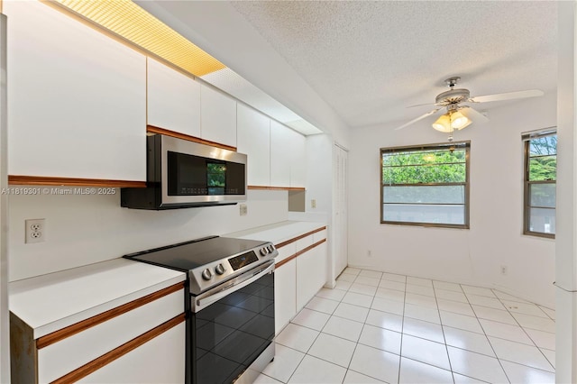 1704 Andros Isle Unit C2, Coconut Creek, FL 33066 - kitchen with stainless steel appliances, healthy amount of natural light, white cabinetry, light countertops, and a textured ceiling