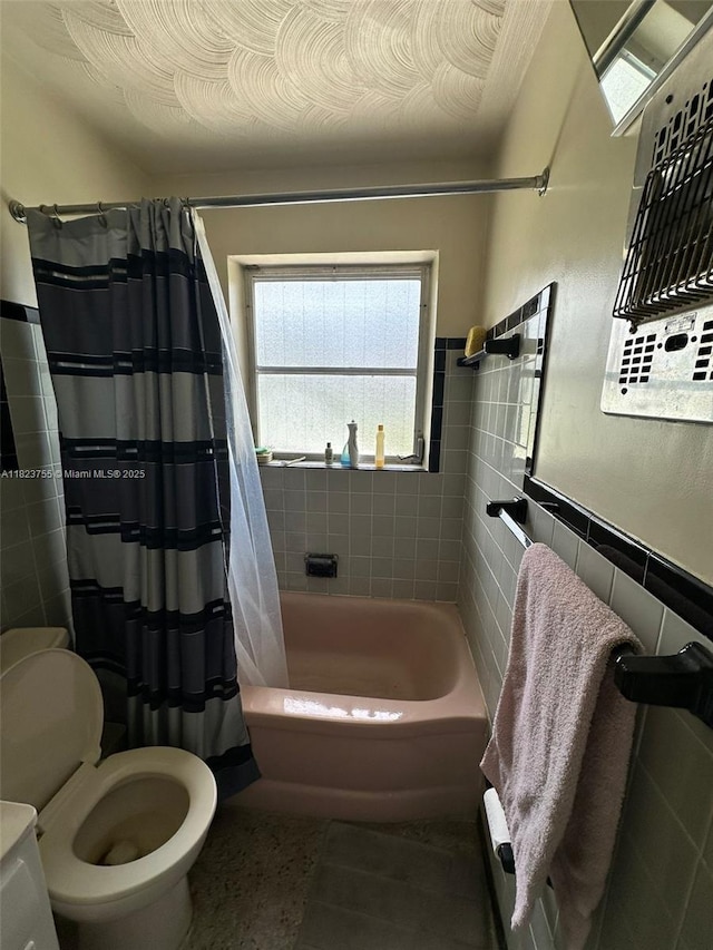 3180 NE 10th Ter, Pompano Beach, FL 33064 - bathroom with tile walls, shower / bath combo with shower curtain, and a wainscoted wall