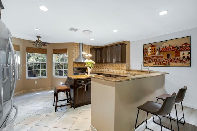 10901 SW 31st St, Davie, FL 33328 - kitchen featuring wall chimney exhaust hood, freestanding refrigerator, a kitchen breakfast bar, a peninsula, and tasteful backsplash