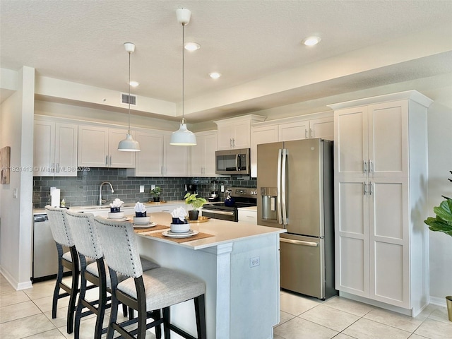 4751 Clock Tower Dr Unit 307, Kissimmee, FL 34746 - kitchen featuring stainless steel appliances, light tile patterned floors, light countertops, and a kitchen island