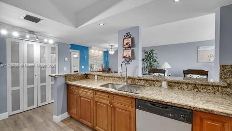 200 Leslie Dr Unit 407, Hallandale Beach, FL 33009 - kitchen featuring stainless steel dishwasher, light stone counters, light wood-type flooring, and brown cabinets