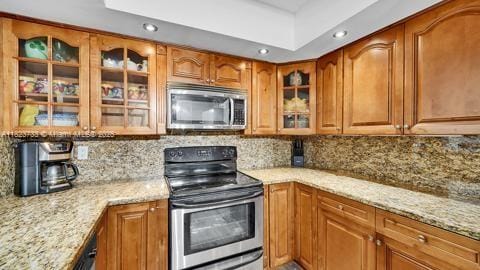 200 Leslie Dr Unit 407, Hallandale Beach, FL 33009 - kitchen with appliances with stainless steel finishes, brown cabinetry, light stone countertops, glass insert cabinets, and recessed lighting
