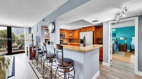 200 Leslie Dr Unit 407, Hallandale Beach, FL 33009 - kitchen featuring stainless steel appliances, brown cabinets, light wood-style floors, a breakfast bar area, and floor to ceiling windows