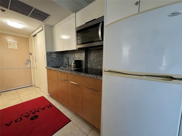 19201 Collins Ave Unit 1137, Sunny Isles Beach, FL 33160 - kitchen featuring freestanding refrigerator, stainless steel microwave, black electric cooktop, light tile patterned floors, and tasteful backsplash