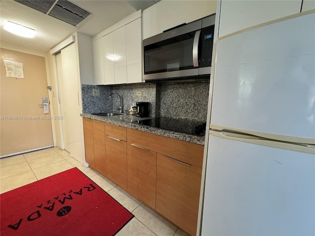 19201 Collins Ave Unit 1137, Sunny Isles Beach, FL 33160 - kitchen featuring freestanding refrigerator, stainless steel microwave, black electric cooktop, backsplash, and light tile patterned floors