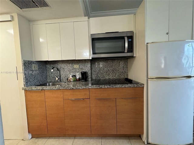 19201 Collins Ave Unit 1137, Sunny Isles Beach, FL 33160 - kitchen with freestanding refrigerator, stainless steel microwave, dark stone counters, and decorative backsplash