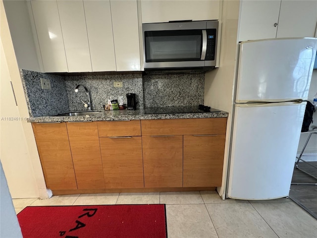 19201 Collins Ave Unit 1137, Sunny Isles Beach, FL 33160 - kitchen with stainless steel microwave, freestanding refrigerator, black electric cooktop, backsplash, and light tile patterned floors
