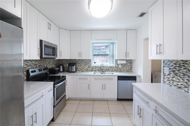 6459 Evans St, Hollywood, FL 33024 - kitchen featuring stainless steel appliances, tasteful backsplash, white cabinets, light tile patterned flooring, and light stone countertops