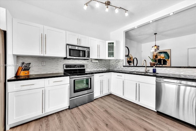 12926 SW 50th St, Miramar, FL 33027 - kitchen with appliances with stainless steel finishes, white cabinets, dark countertops, light wood-style flooring, and tasteful backsplash