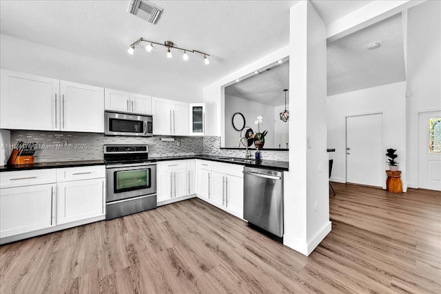 12926 SW 50th St, Miramar, FL 33027 - kitchen with appliances with stainless steel finishes, dark countertops, light wood-type flooring, white cabinetry, and tasteful backsplash