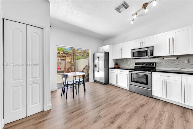 12926 SW 50th St, Miramar, FL 33027 - kitchen featuring appliances with stainless steel finishes, dark countertops, backsplash, white cabinets, and a textured ceiling