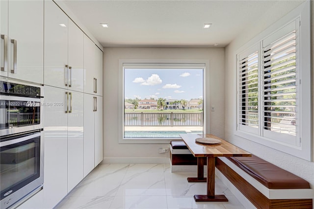 8965 NW 174th Ln, Hialeah, FL 33018 - kitchen with stainless steel double oven, white cabinets, a water view, modern cabinets, and light marble finish floors