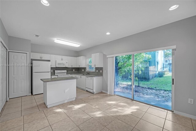 2903 SE 15th Ter, Homestead, FL 33035 - kitchen featuring white appliances, white cabinetry, light tile patterned floors, a kitchen island, and healthy amount of natural light