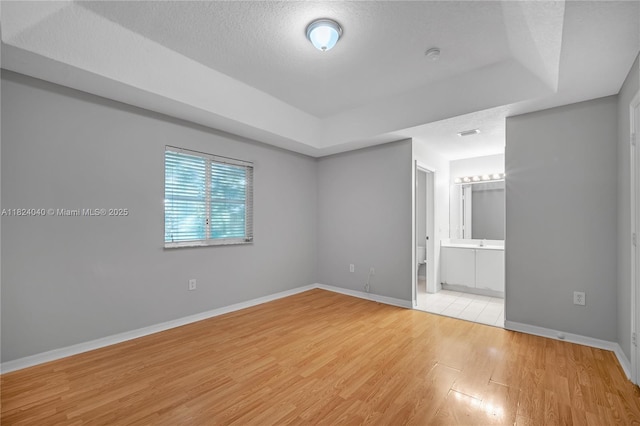 2903 SE 15th Ter, Homestead, FL 33035 - unfurnished bedroom featuring light wood finished floors, a textured ceiling, and a tray ceiling