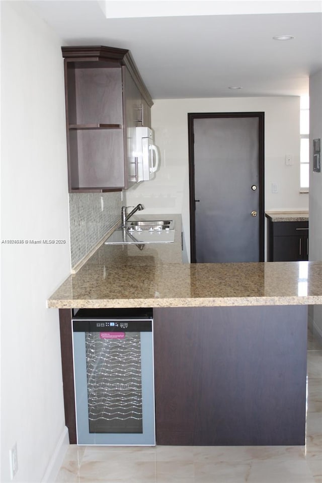 2930 Point E Dr Unit E309, Aventura, FL 33160 - kitchen with wine cooler, white microwave, dark brown cabinets, decorative backsplash, and a peninsula