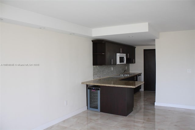 2930 Point E Dr Unit E309, Aventura, FL 33160 - kitchen featuring wine cooler, white microwave, tasteful backsplash, a peninsula, and light marble finish flooring